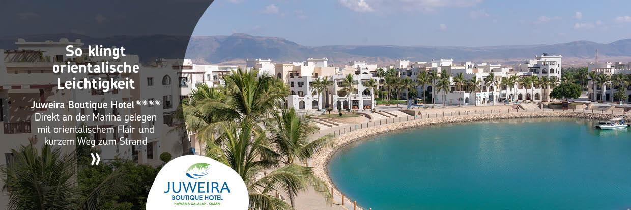 Blick auf eine gebogene Strandpromenade mit Palmen und weißen Gebäuden im Hintergrund unter blauem Himmel.