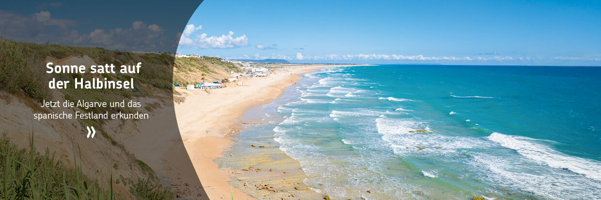 Strand mit Sanddünen und Wellen an der Küste der Iberischen Halbinsel unter blauem Himmel