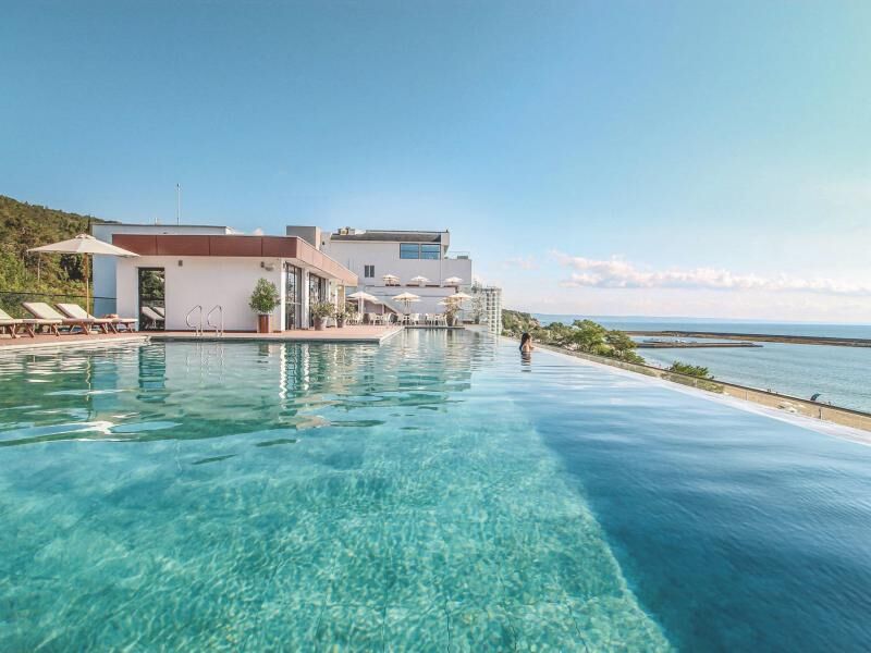 Infinity-Pool mit klarem Wasser vor modernem, weißem Gebäude