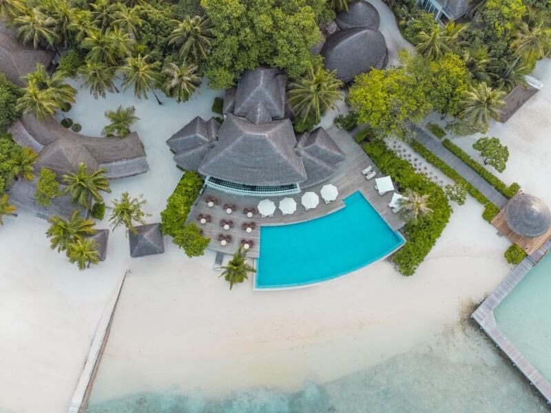 Luftaufnahme eines tropischen Resorts mit mehreren strohgedeckten Gebäuden