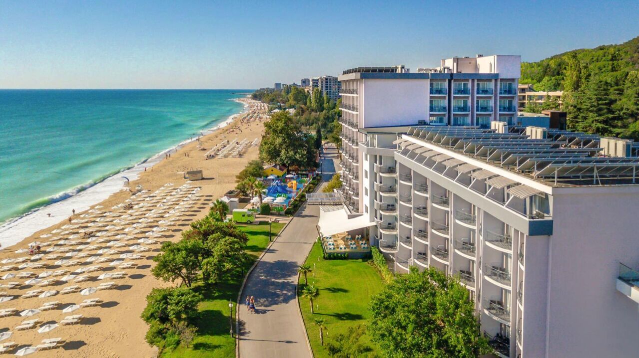 Blick auf einen langen Sandstrand mit vielen Liegen und Sonnenschirmen