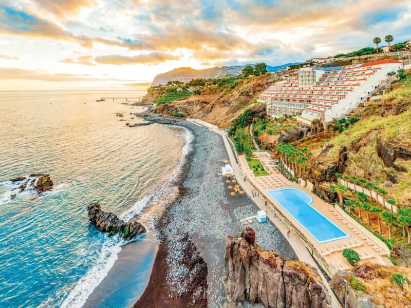Küstenabschnitt mit Felsenstrand, angrenzendem Hotelkomplex und großem Außenpool