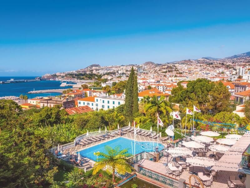 Blick auf einen Hotelpool mit Liegestühlen und Sonnenschirmen