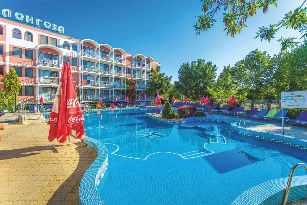 Außenpool mit blauer Wasserfläche vor einem mehrstöckigen Hotelgebäude