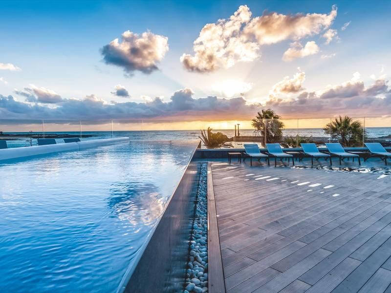 Infinity-Pool mit Holzterrasse und Liegestühlen