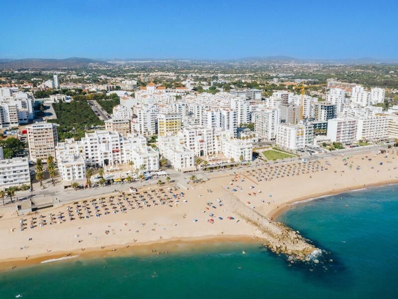 Strand mit Sonnenschirmen und dahinter dicht bebautes Stadtgebiet