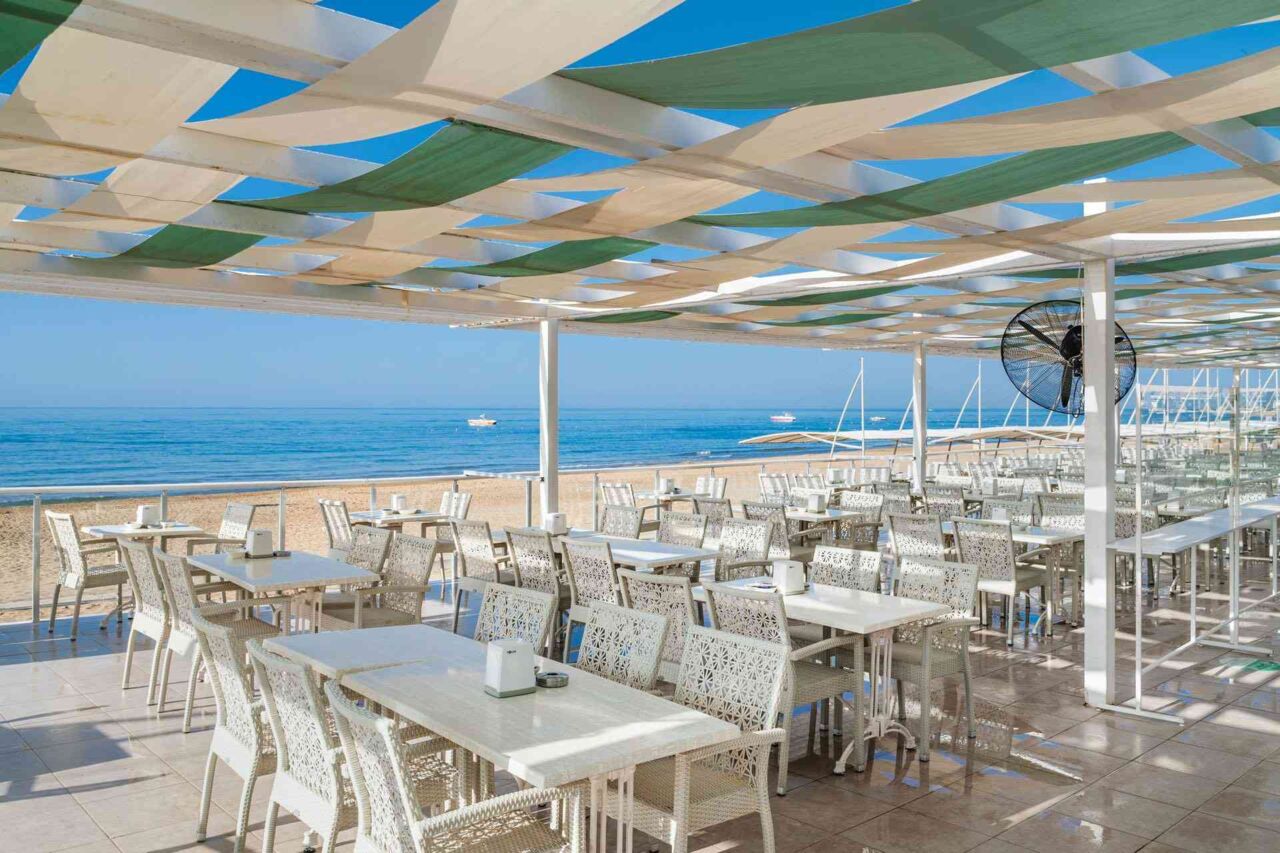 Überdachte Terrasse mit weißen Tischen und Stühlen