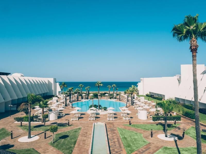 Blick auf einen Hotelpool mit Liegestühlen und Sonnenschirmen