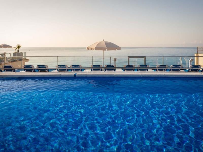 Blick über einen blauen Pool mit Liegestühlen