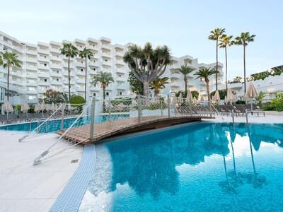 Pool mit Bogenbrücke vor mehrstöckigen Hotelgebäude