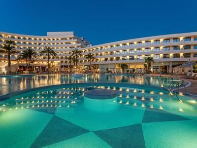 Hotelgebäude mit beleuchtetem Pool bei Abenddämmerung
