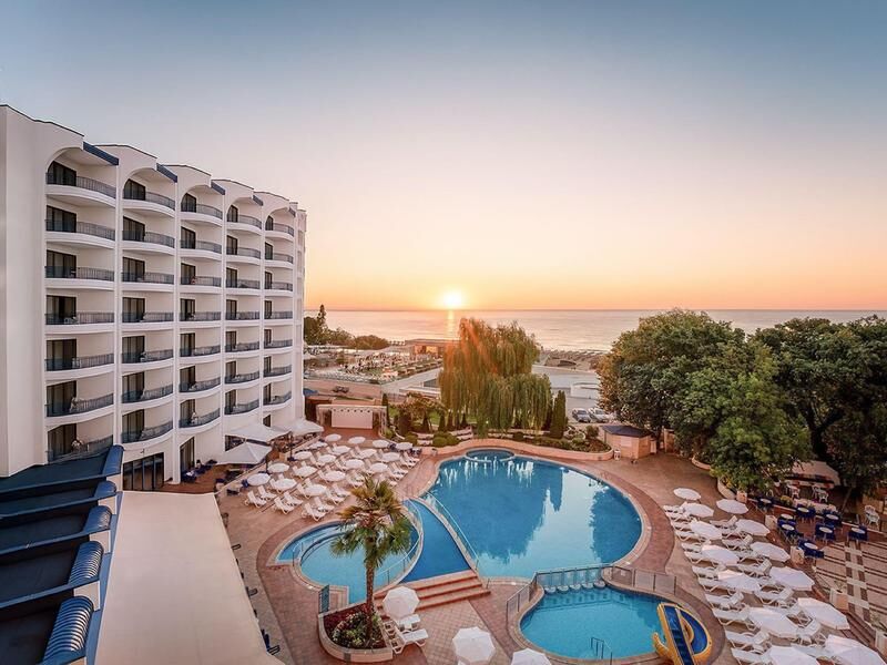 Hotelgebäude mit Balkonen neben einem großen Pool mit Liegestühlen