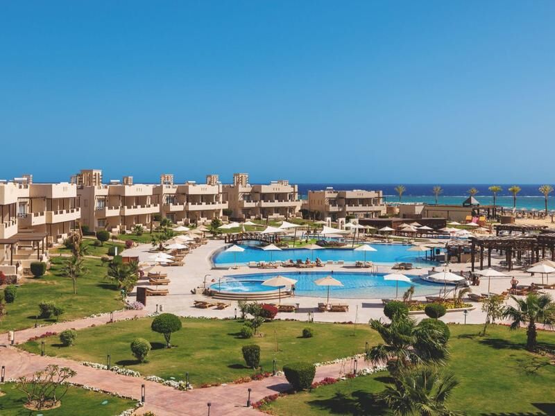 Blick auf eine Hotelanlage mit mehreren Pools, Sonnenschirmen