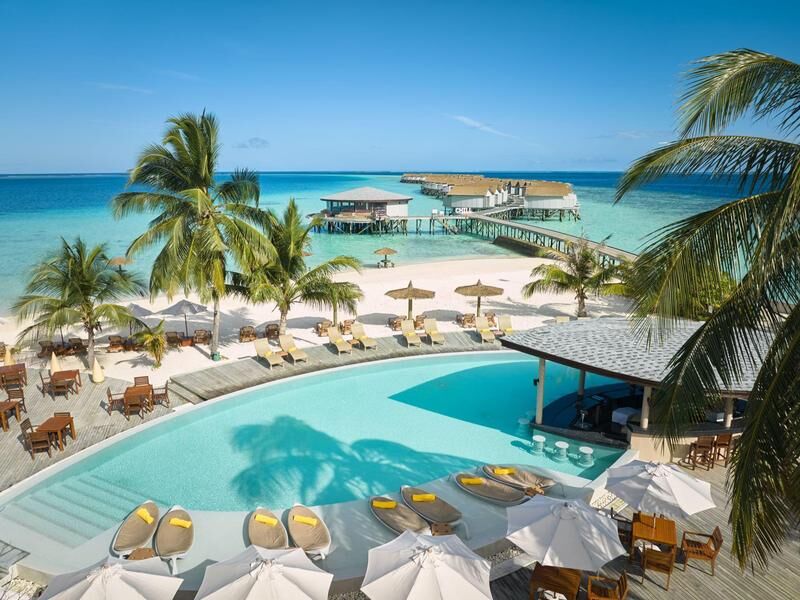 Blick auf einen tropischen Strand mit Palmen, einem Pool