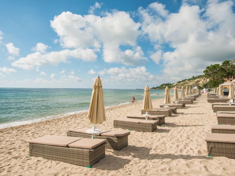 Strand mit einer Reihe von Liegen und geschlossenen Sonnenschirmen