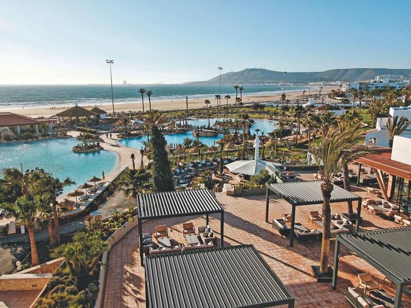 Blick auf eine weitläufige Hotelanlage mit mehreren Pools, Liegestühlen