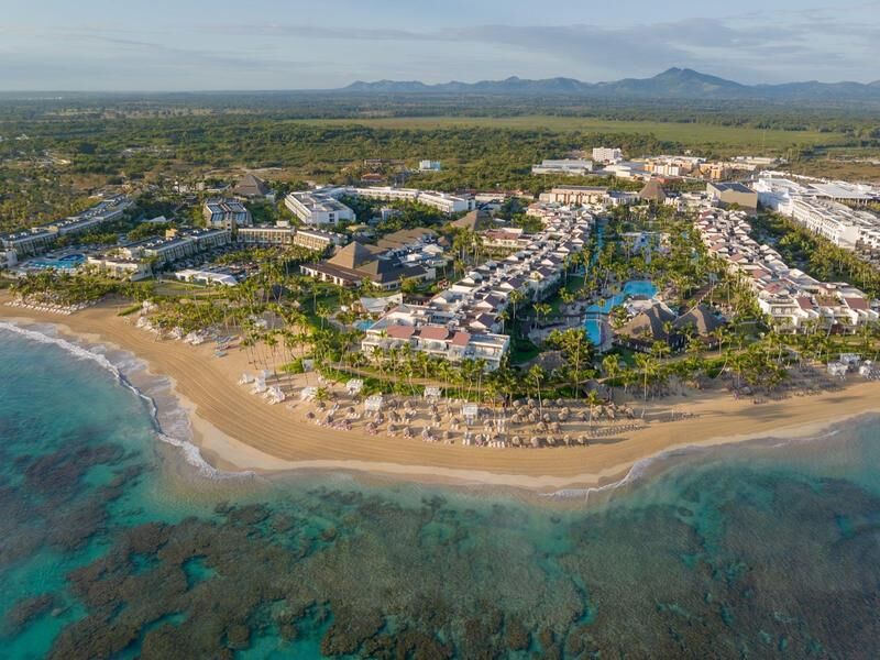 Luftaufnahme eines großen Strandresorts mit mehreren Pools, umgeben von Palmen und angrenzendem Sandstrand mit Liegestühlen