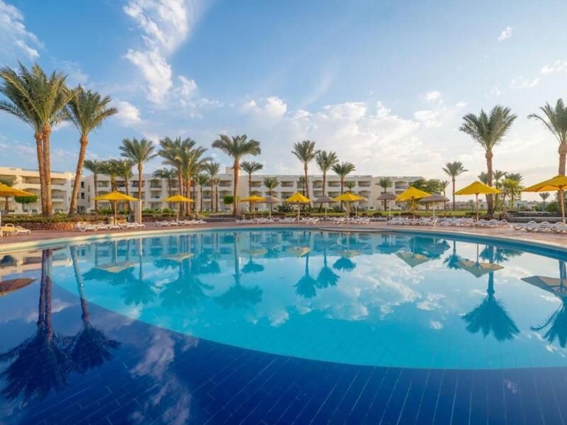 Großer Pool mit spiegelglatter Wasseroberfläche vor mehrstöckigem Hotelgebäude