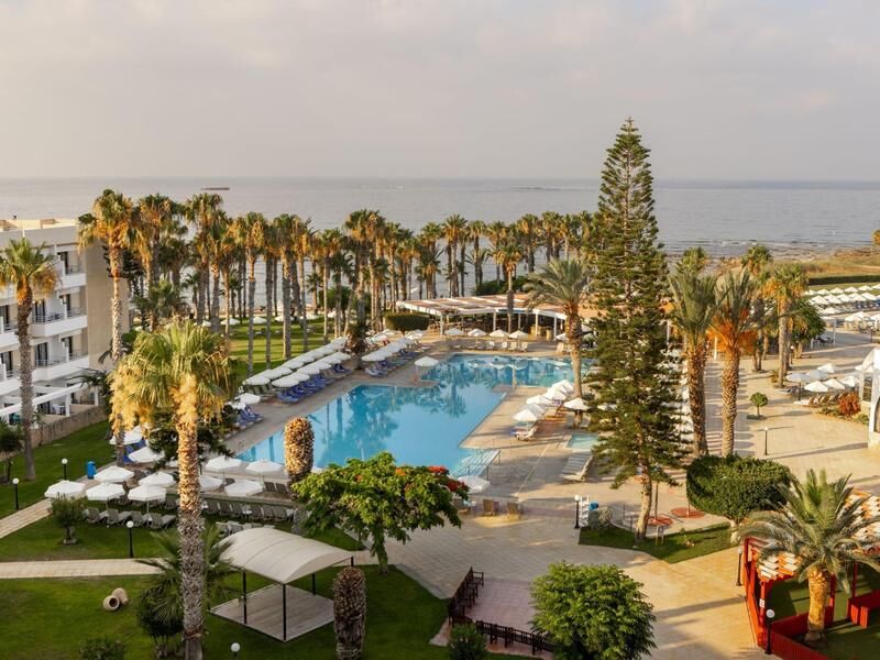 Hotelpool mit Liegen und Sonnenschirmen umgeben von Palmen