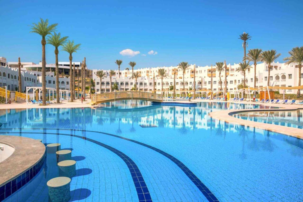 Großer Hotelpool mit runden Sitzstufen im Wasser, umgeben von Liegestühlen
