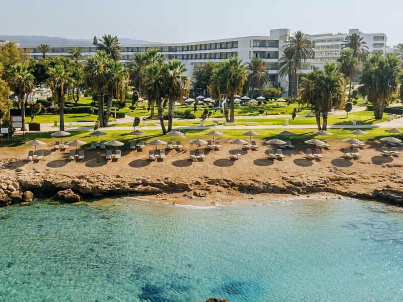 Strand mit Sonnenschirmen und Liegen vor einem Hotelgebäude