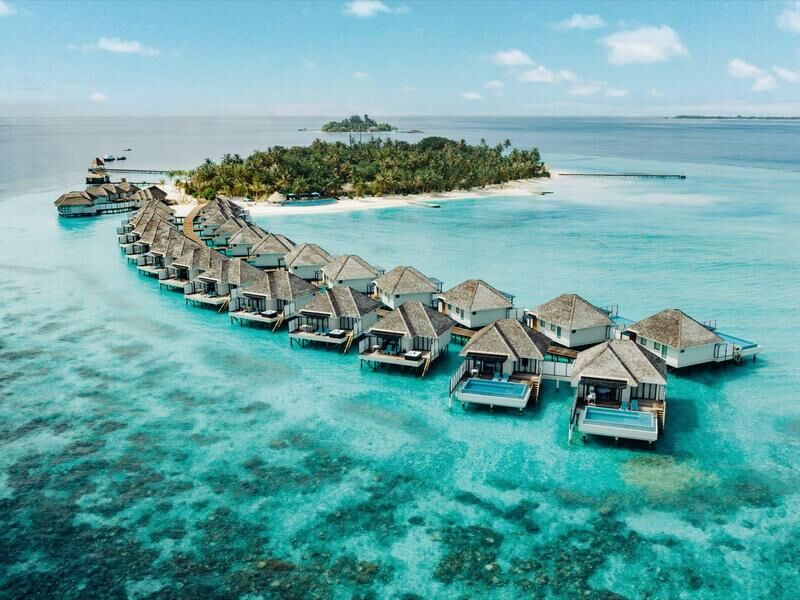 Reihe von über Wasser gebauten Bungalows mit Strohdächern