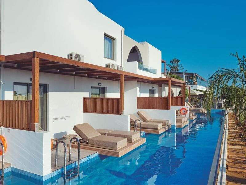 Hotel mit weißen Wänden und davor ein langer Pool