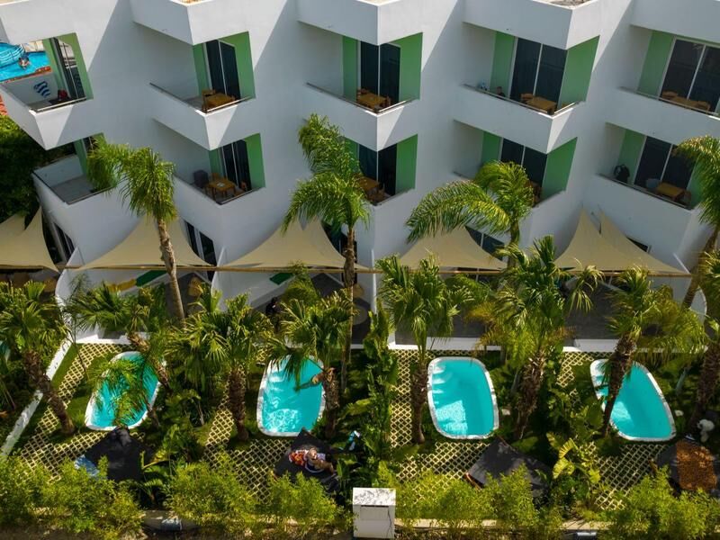 Mehrere kleine Pools vor einem weißen Hotelgebäude