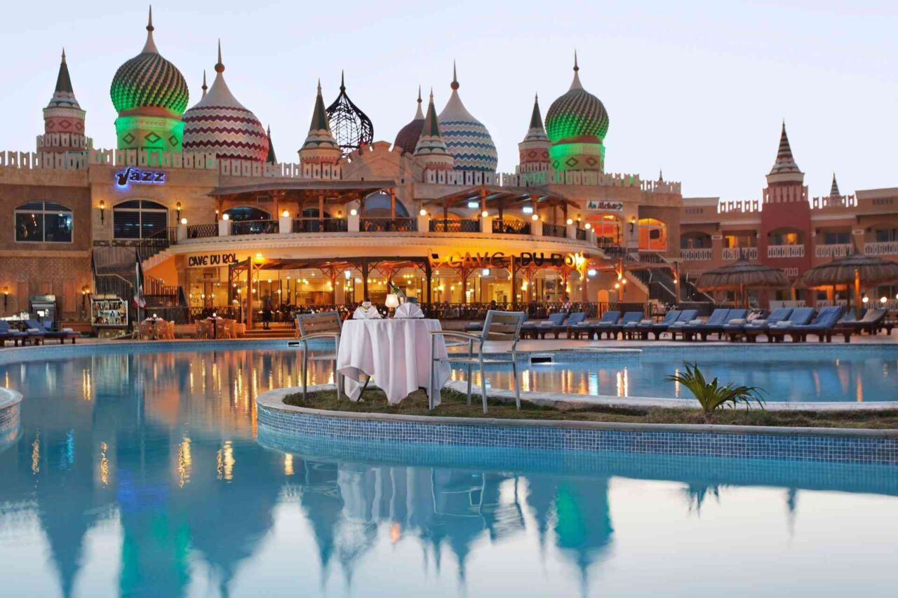 Außenrestaurant mit gedecktem Tisch auf einer Insel in einem großen Pool vor einem Gebäude