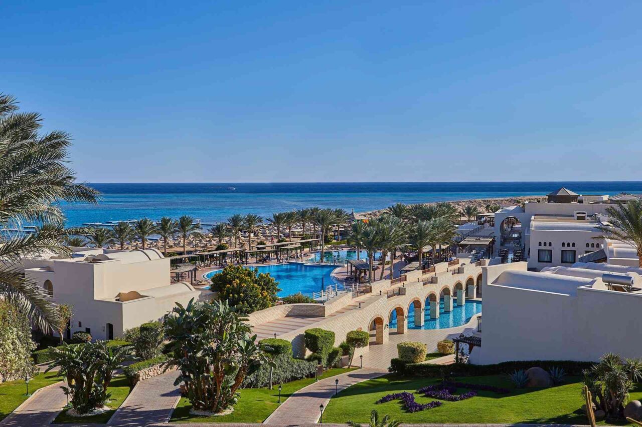 Blick auf ein Resort mit Pool, Palmen und weißen Gebäuden
