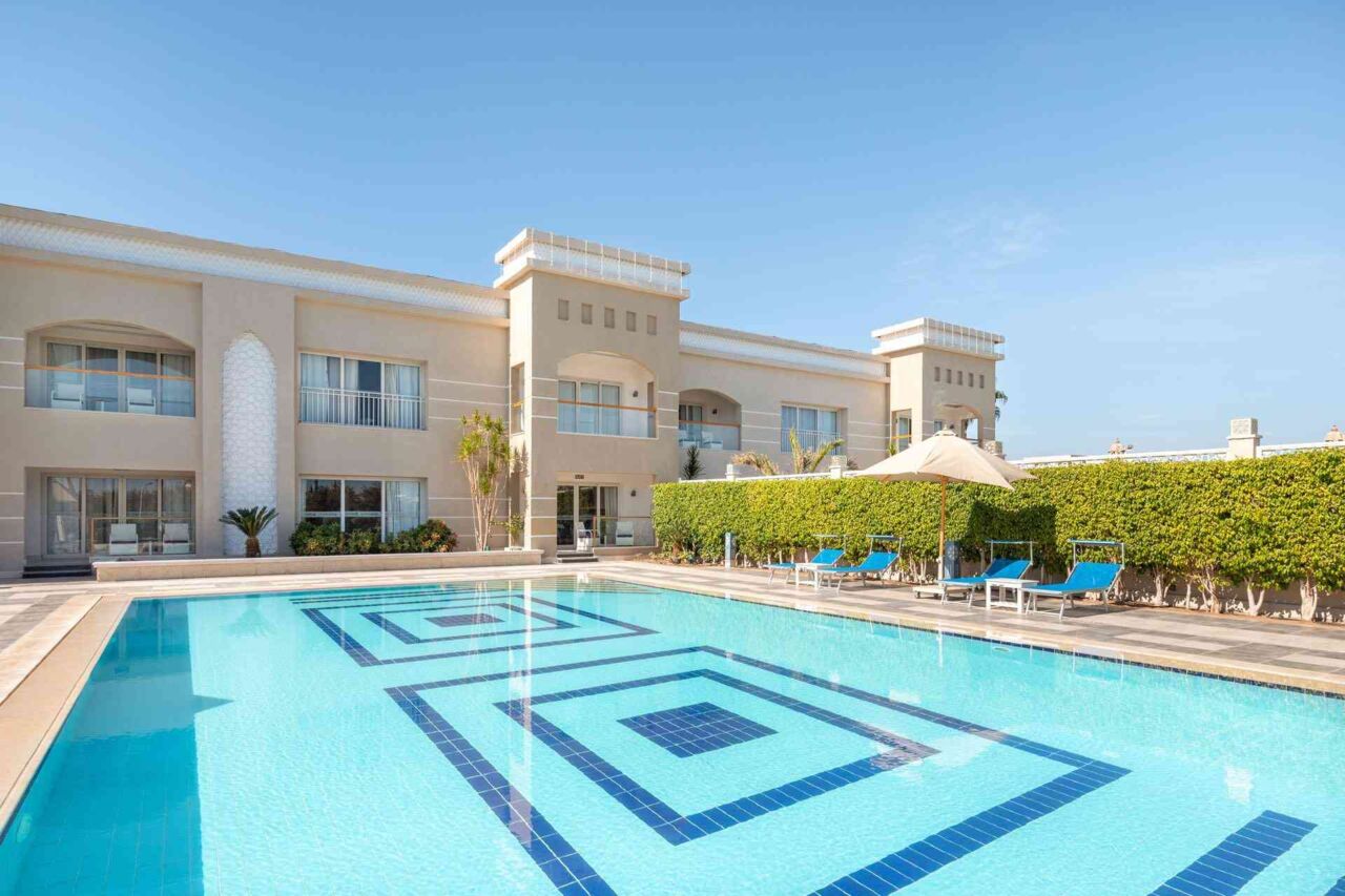 Großer rechteckiger Pool mit geometrischem Muster vor einem zweistöckigen Gebäude