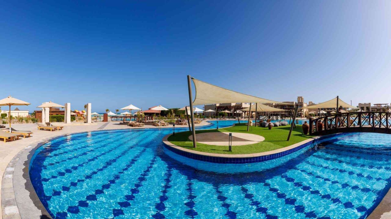 Großer Pool mit geschwungener Form, Insel mit Sonnensegel und Brücke