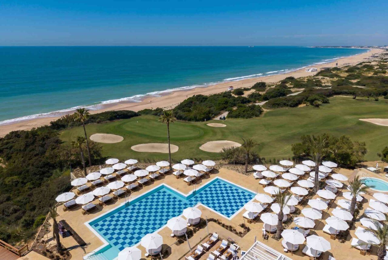 Blick auf einen Pool und dahinter ein Strand am Meer