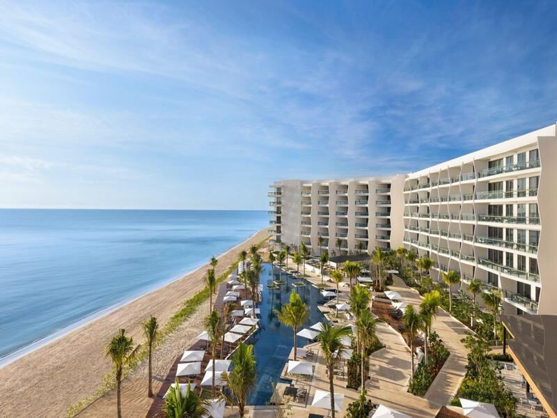 Modernes Hotel mit Pool, umgeben von Palmen am Meer